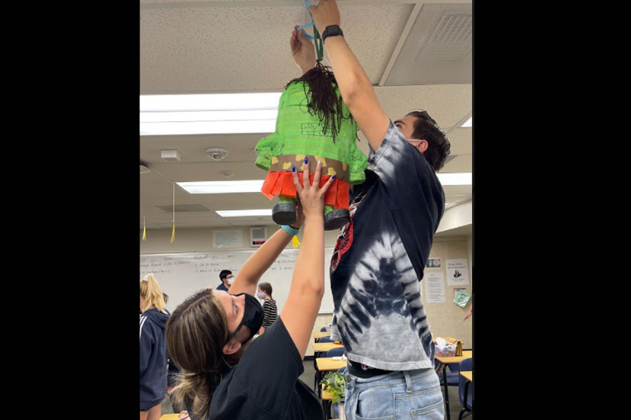 Senior AP English APEs Lesly Hernandez and Nick Parks hang a Trog pinata in the AP U.S. History classroom as part of the class-rivalry ritual. 