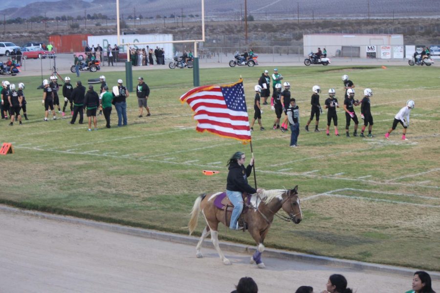 Ashley Hannah and her horse Patch carry the stars and stripes around the track for the Homecoming game. 