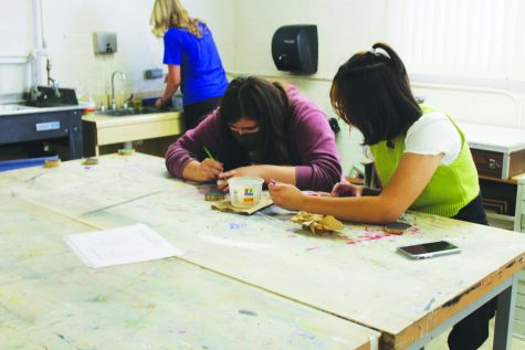 Sophomore Chloe Godfrey and freshman Yohanna Ramos work on wood-slice ornaments for their Art Club fundraiser. 
