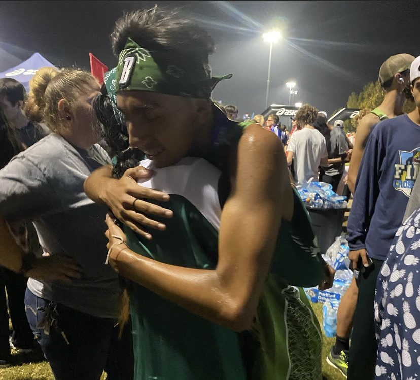 Sophomore Zion Ortiz hugs his mom, Laura Ortiz after he ties his dads Cross Country record of 14:43.
