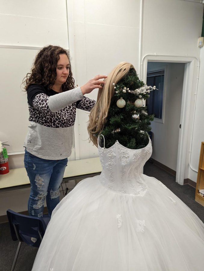 Junior Avery Thibado decorates the Friends of Rachel Christmas tree which features a dress from Rachels Closet.