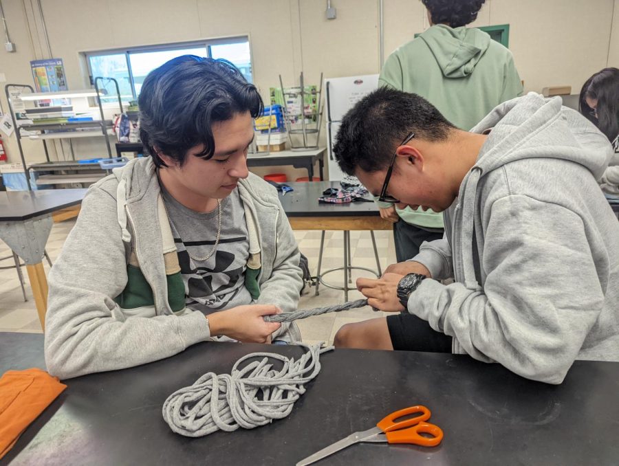 Senior Matthew Sorenson and junior Kelvin Panergo learn how to braid old t-shirts into dog toys for a Key Club service project.