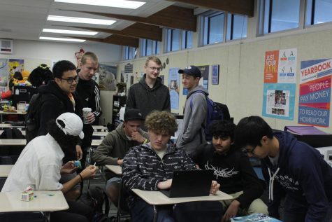 Juniors Isaac Eggleston and Sam Andrus (seated center) gather with their friends before school to complete a quick online chess match. 