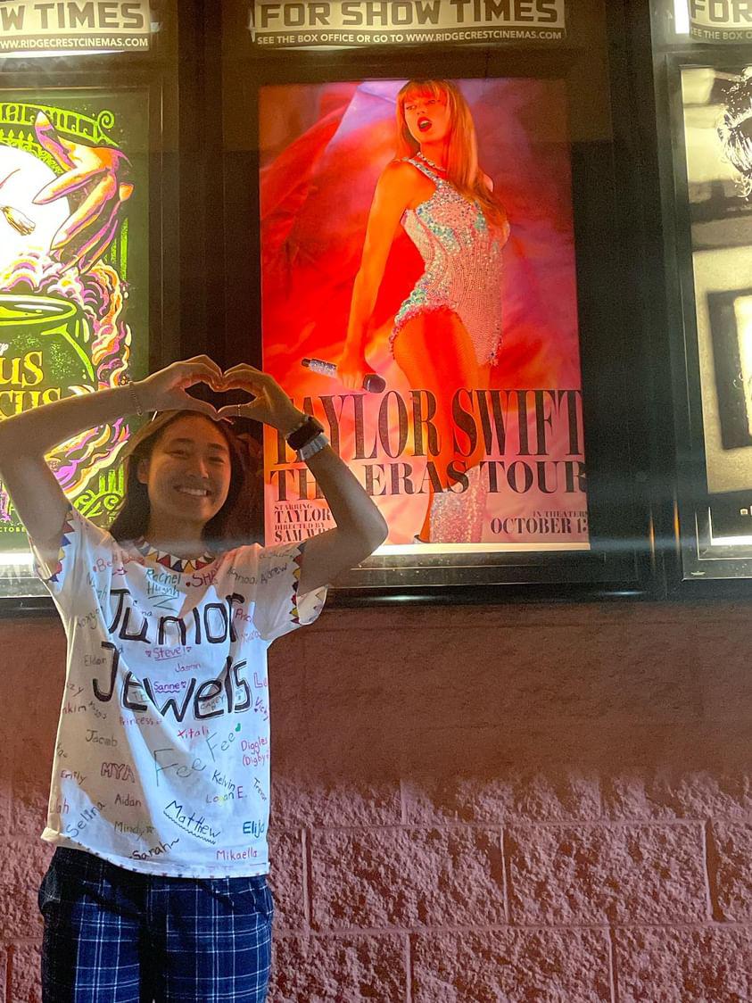 Senior Amanda Huynh poses in front of the Taylor Swift Eras Tour Movie Poster in her Junior Jewels outfit