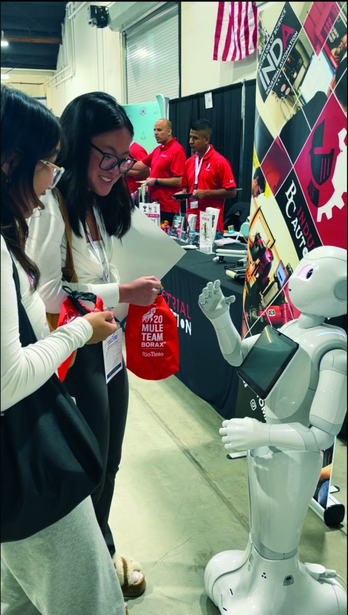 Juniors Lynkim Phan and Julia Hechanova converse with a robot at the Bakersfield College Industrial Automation booth at the East Kern Career Expo.  