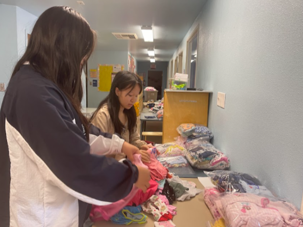 Freshmen Tamanh Nguyen and Annie Ngo prepare bags of baby clothes.