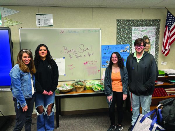 Engilsh teacher Rosemary Gilbert and seniors Karla Cisneros, Hailey Farmer, and Stephen Rogers proudly stand with their display of baked goods.