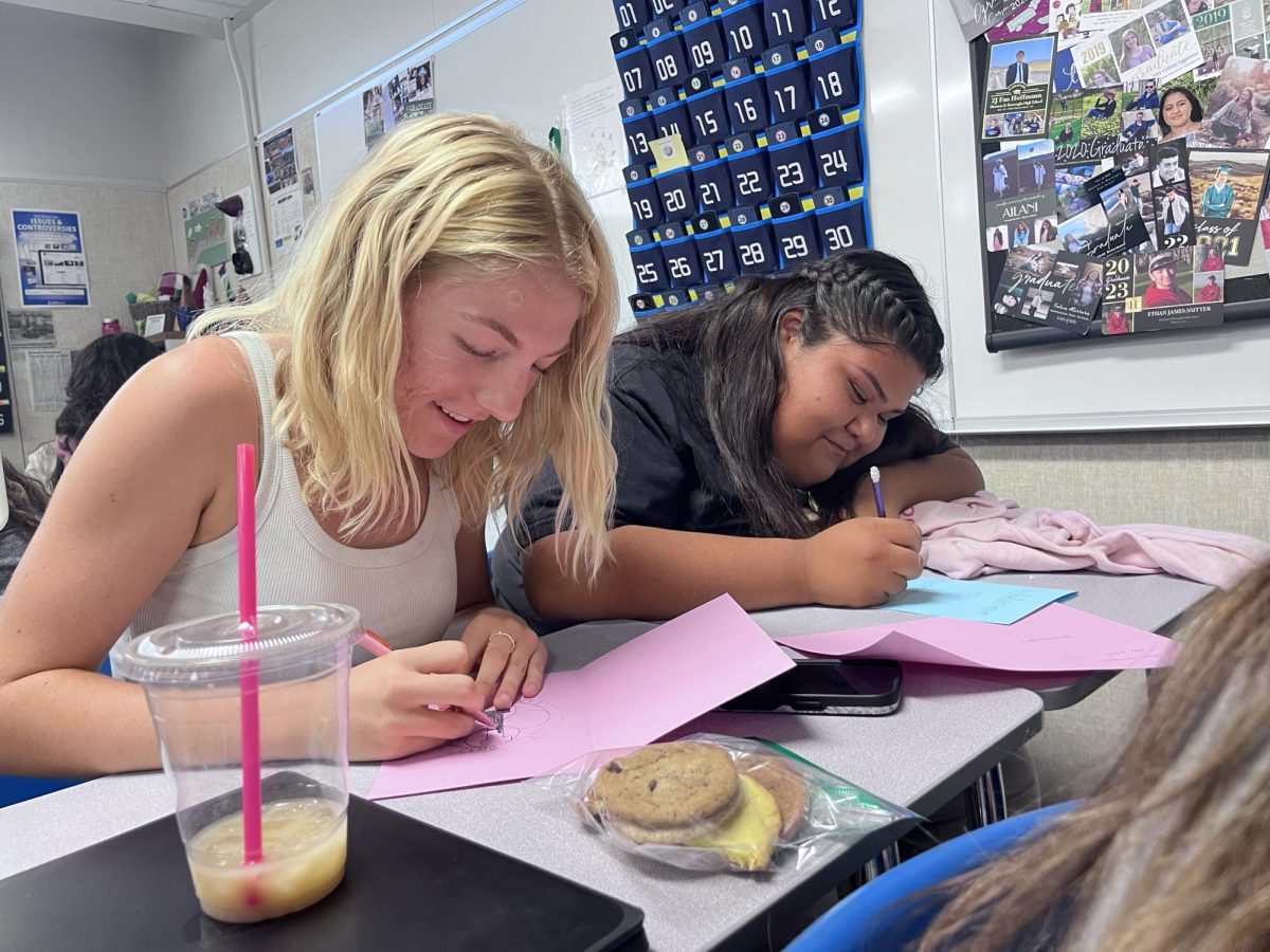 Interact Club members juniors Paige Dunn and Bianca Cabrera decorate cards to hand out, along with cookies, to new Burroughs teachers to welcome them to the school.