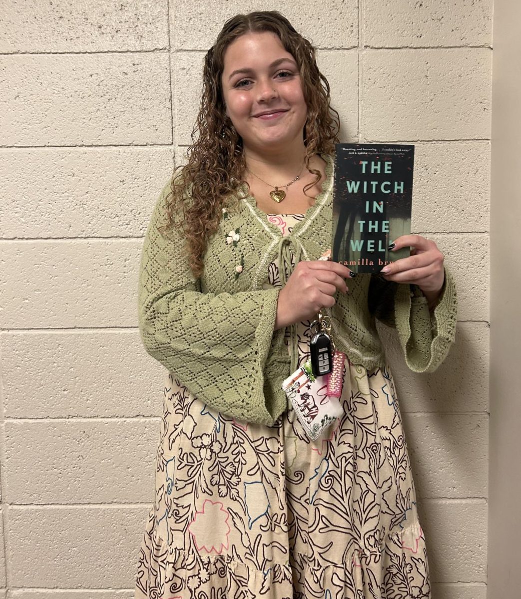 Book Club President Haley Hengsteler, a junior, poses with Book Club's current read.  