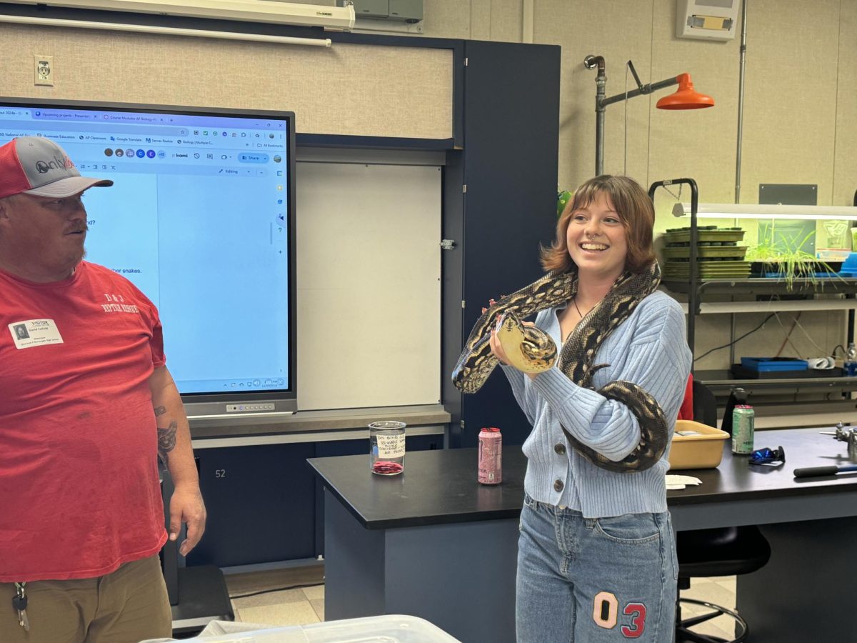 On November 15, D+J Reptile Rescuing and Re-homing came to Melanie Branson's Zoology class to teach students about the true nature of snakes so that they wouldn't be as afraid. David Cofield guides zoology student Francis Thornton as she holds a live Boa Constrictor.