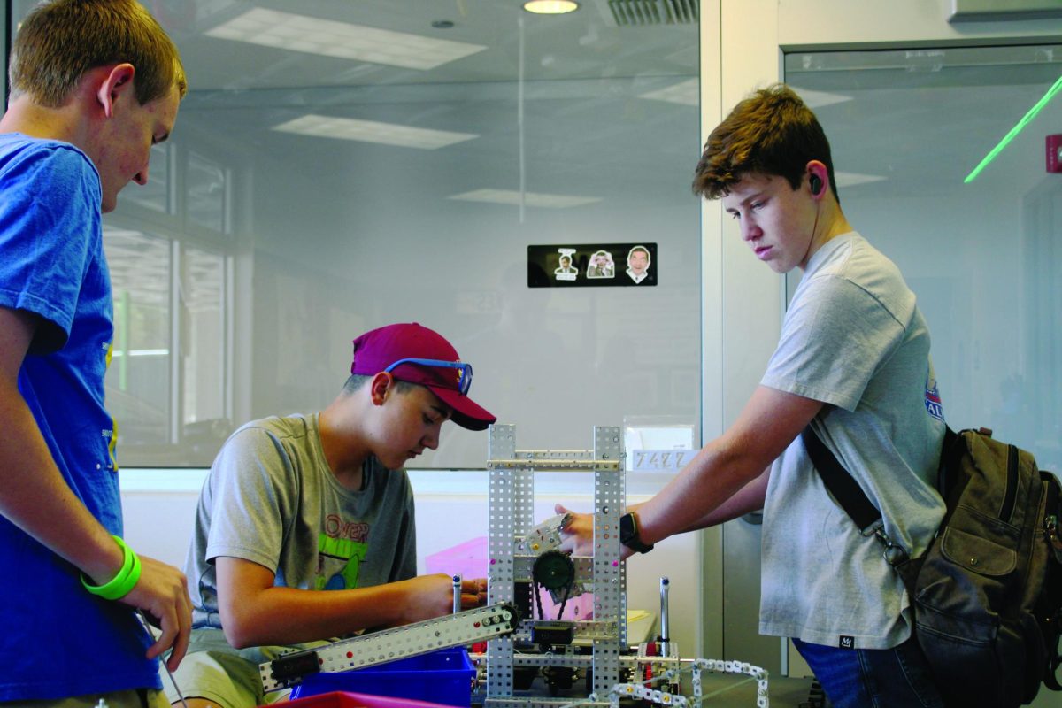 Team 7422C members Zach Duchow, Liam Staheli, and Talen Houck test the revolver mechanism on their 2025-2026 robot.