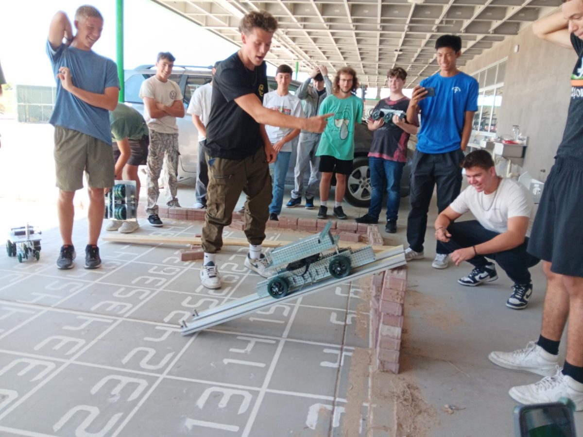 Junior Everett Dickey cheers on his team's robot while it climbs up the incline plane during a recent competition in Principles of Engineering.