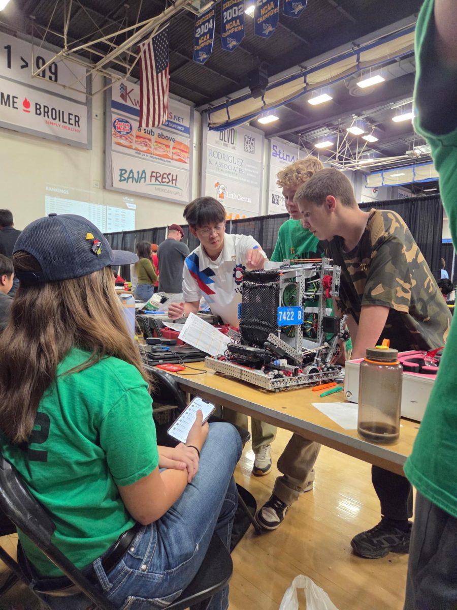 7422B members Grant MacGregor, Samuel DeMaris, and Charleigh Davis discuss their robot's capabilities with their next alliance partner, coming up with the best strategy to win the match.