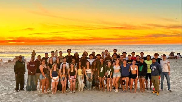 Burroughs track and field athletes pose for a sunset photo on the beach in San Diego. 