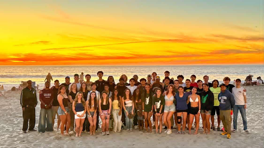 Burroughs track and field athletes pose for a sunset photo on the beach in San Diego.